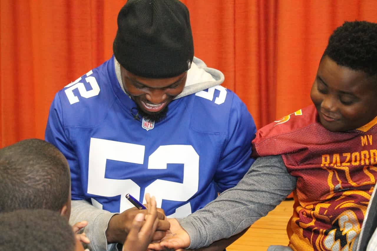 New York Giants lineman Alec Ogletree signs autographs for Mount Vernon City School District students at Domestic Violence Awareness Month event held at Traphagen School.