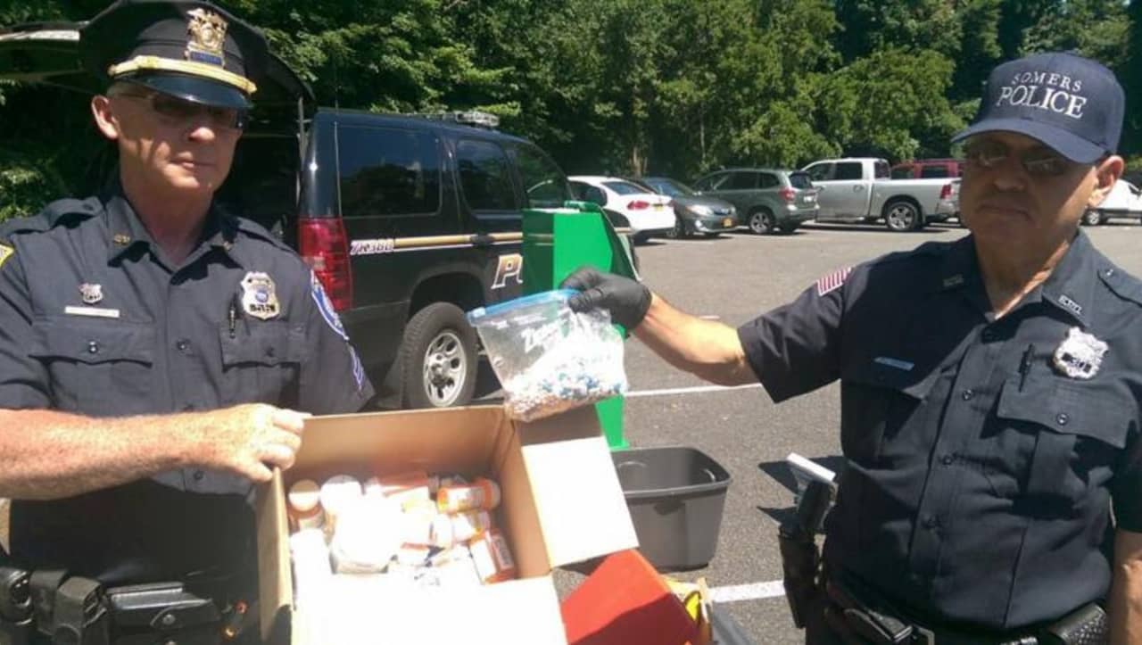Somers Police Chief Michael Driscoll, left, and an unidentified police officer, display some of the medications collected in June at the Somers Town House. 