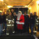 Teaneck firefighters and Santa gear up at the department before making special deliveries.