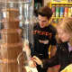 A Chocolate Works employee helps a customer get the most out of the chocolate fountain.