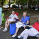 A group of ladies enjoy the sunny day under the shade during the car show.