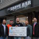 Outside The Shave Bar for a pre-shave pose holding a symbolic check for the $3,792 Hillsdale police raised for cancer research during No-Shave November.