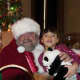 A young girl visits with Santa and his Elf.