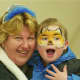 A woman and a child with a painted face enjoying the activities.