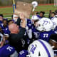 New Rochelle coach Lou DiRienzo hoisting the Section 1 championship trophy with his players.
