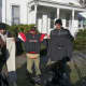 Four men hold up coats and clothing items they received at the mission.