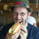 Noshi's owner Peter Newman takes a bite out of one of his trademark hot dogs.