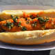 Hot dog topped with roasted pumpkin topping with parmesan cheese, sage, and roasted pepitas.