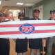 The staff of Jersey Mike's in East Rutherford proudly show off the surfboard that hangs in the shop as a  reminder of its Jersey shore origins.