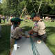 Troop 53 Scouts teach a visitor how to make rope.