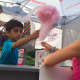 A young volunteer distributes cotton candy.