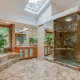The bathroom features wall to wall stonework and both windows and a skylight.
