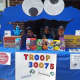 A Girl Scout troop sells cookies from a "Cookie Monster" booth.