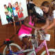 Lucia Villani helps Grace Bennett onto her new pink bike at the White Plains YMCA Wednesday. 