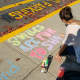 Parent Brieana Kennedy draws "smiles are fun to share," at Kings Highway Elementary School on Friday, Oct. 17, as a part of the Kindness in Chalk movement.