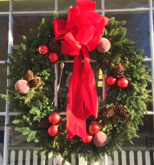 A deli in Bedford displays a plump Christmas wreath covered with fruits and pine cones.