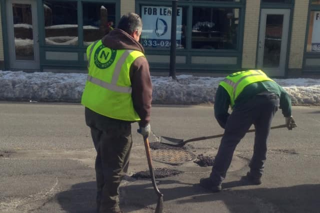 A Department of Public Works crew in Norwalk repairs potholes on Water Street.