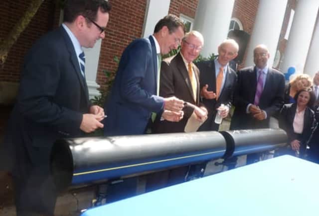 Gov. Dannel P. Malloy, second from left, jokes with Wilton First Selectman Bill Brennan, center, after they and other officials signed an 8-inch polyethylene pipe during a press conference Monday announcing the expansion of Yankee Gas into the town. 