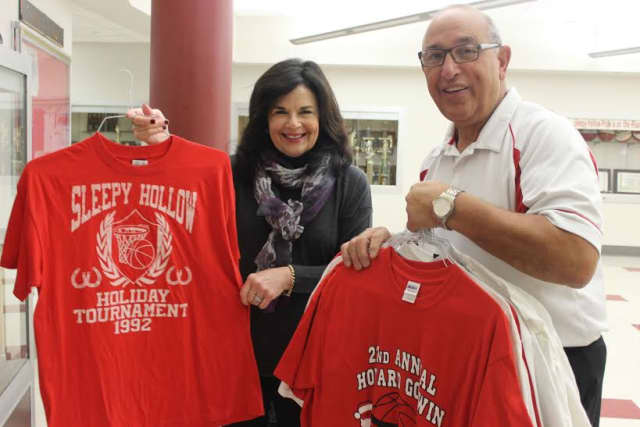 Tarrytown Schools Board of Education President Mimi Godwin and Tarrytown Union Free School District Athletic Director Chuck Scarpulla hang commemorative T-shirts in the lobby of the school gymnasium in preparation for the holiday tournament.