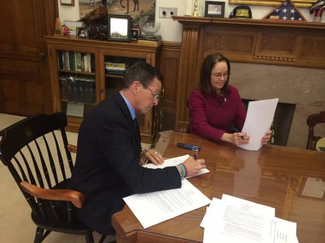 Gov. Dannel Malloy signs the executive order Monday in his office. 