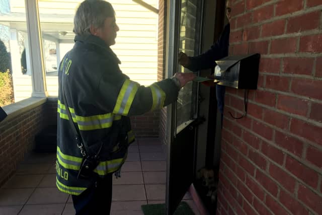 The American Red Cross will be visiting South Norwalk to help residents learn how to be prepared in case of home fires. Above, Fire Inspector Kurt McDonald hands fire safety information to a resident after fatal fire on Ely Avenue last month. 