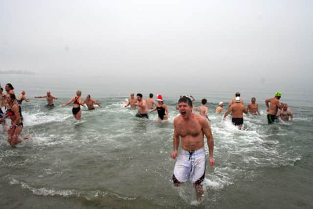 Participants in a past year's Team Mossman Polar Plunge at Westport's Compo Beach brave the icy waters of Long Island Sound for charity. 