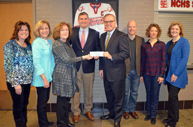 A $10,000 check was presented to New Canaan High School Principal Dr. Bryan Luizzi from the Bradley J. Fetchet Memorial Foundation in front of his high school hockey jersey. 