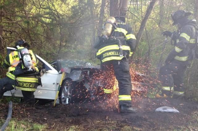 Fairfield firefighters work to put out a car fire after a rollover crash on the Merritt Parkway Sunday evening.